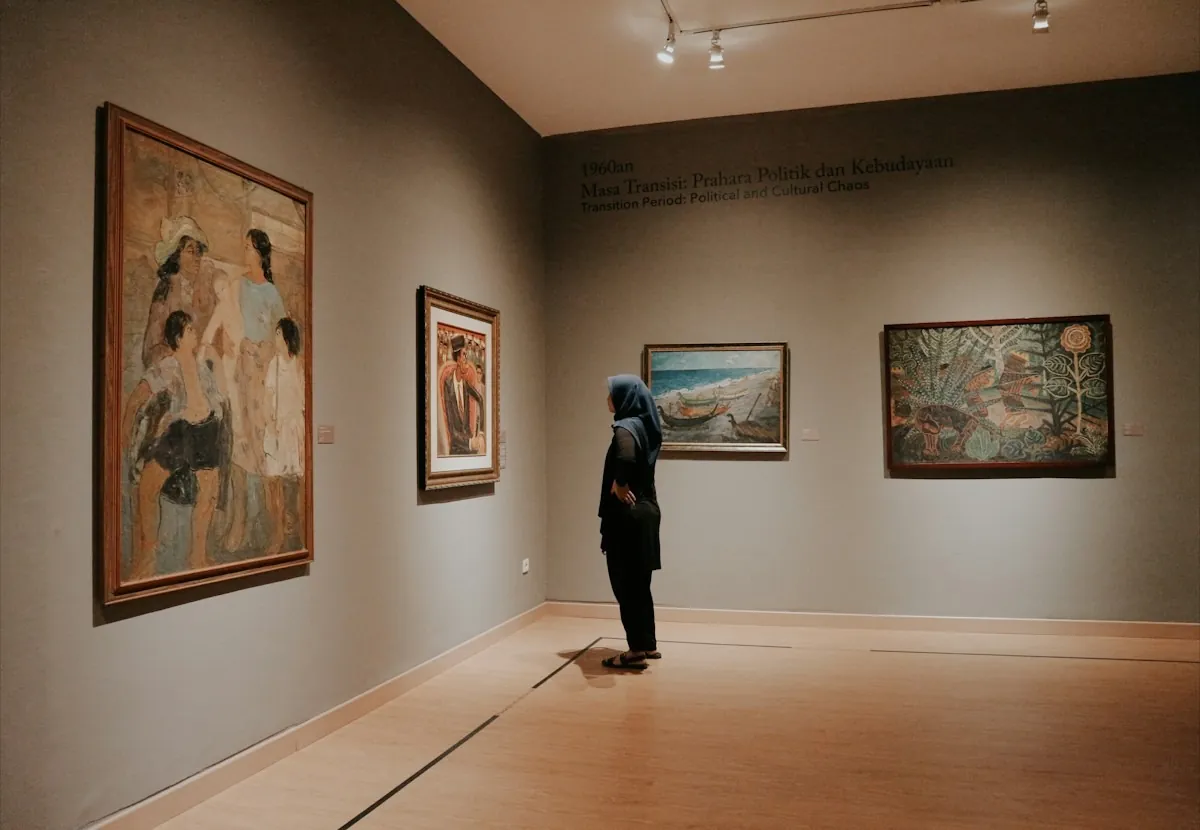 Eine Person betrachtet Gemälde in einem hellen Museumssaal mit Holzboden
